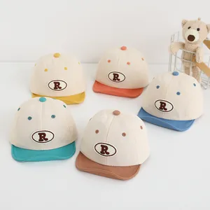 Dettaglio di cinque cappellini da baseball per neonati in cotone con ricamo R