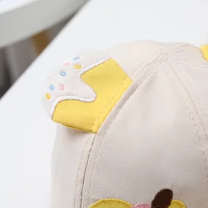 Makrodetail der niedlichen Cupcake-Stickerei und des Twill-Stoffs auf der Babykappe