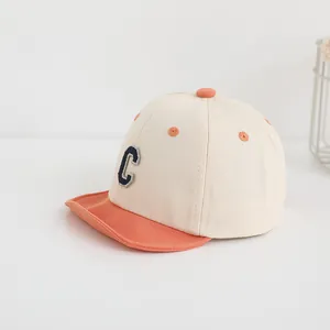Dettaglio del cappellino bimbo con visiera arancione e lettera C ricamata blu