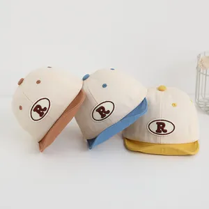 Dettaglio di cappellini da baseball morbidi in cotone per neonati con ricamo R colorato