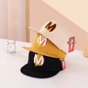 Vista dettagliata di tre cappelli snapback in beige, giallo senape e nero con ricamo M