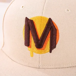 Dettaglio del cappellino hip-hop beige per bambini con lettera M ricamata in 3D multicolore