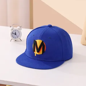 Dettaglio del ricamo della lettera M nera su cappello snapback blu scuro e giallo