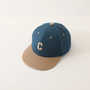 Macro-opname van beige 3D-letter C borduursel op de blauw-khaki tweekleurige kinderpet