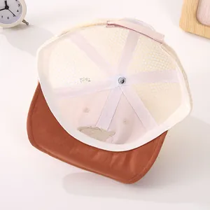 Detail of baby mesh cap showing breathable holes, brown brim, and adjustable strap