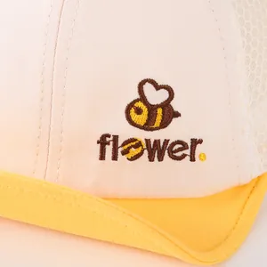 Detalle de gorra de rejilla para bebé con bordado de abeja y texto flower