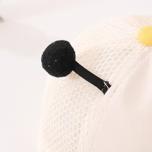 Detalle de gorra infantil con malla transpirable beige, pompón negro y lona suave