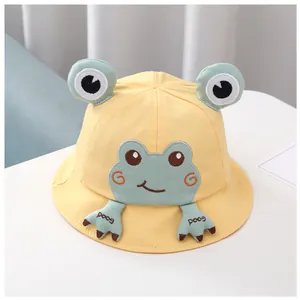 Détail du chapeau de soleil bébé grenouille jaune avec yeux 3D et pattes brodées