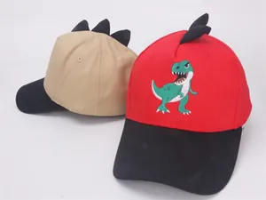 Detailansicht der roten und khakifarbenen Kinder-Baseballkappen mit Dinosaurier-Stickerei