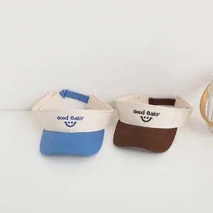 Close-up of baby sun visor hats with Good Baby smile embroidery in blue and brown