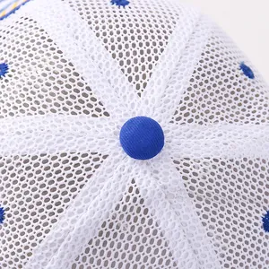 Détail d'une casquette blanche en maille avec œillets brodés bleus et bouton