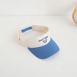 Close-up of blue and white sun visor hat for kids with Good Baby smiley face embroidery