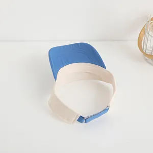 Detail of blue and beige sun visor hat showing canvas texture and adjustable strap