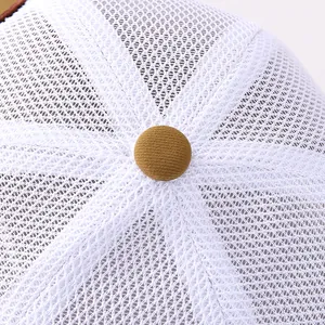 Détail macro du tissu en maille blanche respirante et bouton marron de casquette enfant