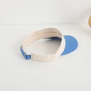 Detail view of adjustable metal buckle and blue strap on children's visor hat