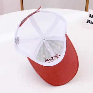 Detail view of red and white mesh trucker hat interior with embroidery and wash label