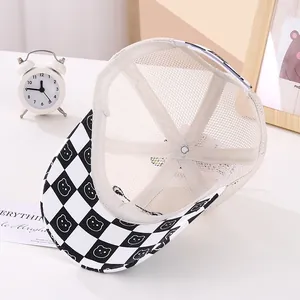 Detail of baby mesh cap featuring cartoon bear checkered brim and breathable beige fabric