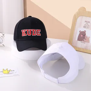 Close-up of black baseball cap with KUDE embroidery and white sun visor on a display stand