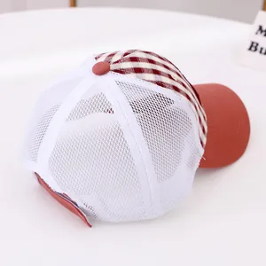 Detail of red-brown checkered fabric and white mesh panels on breathable trucker hat