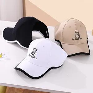 Close-up of three kids baseball caps in black, white and beige with bear embroidery