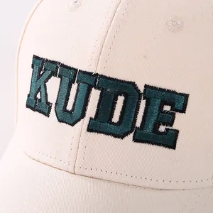 Detailed macro view of KUDE embroidery on beige cotton twill baseball cap fabric