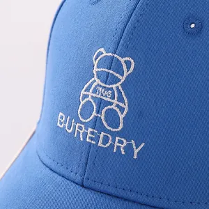 Detail of blue cotton baseball cap featuring embroidered bear logo and white text