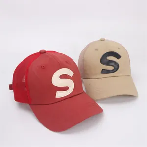 Detail view of red and khaki mesh baseball caps with stitched leather S letter patch