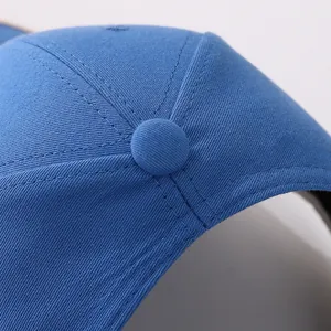 Close-up of blue cotton baseball cap showing top button and reinforced stitching detail