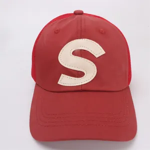 Close-up of red mesh baseball cap with white S patch and reinforced stitched brim