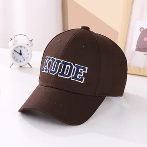 Detail of brown baseball cap featuring KUDE embroidered letters and premium stitching