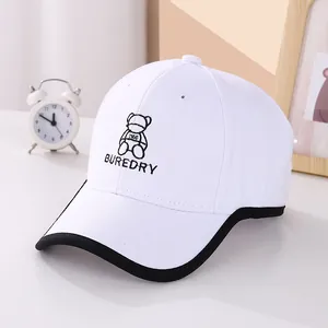 Detail of white cotton kids baseball cap with cute bear embroidery and black brim piping