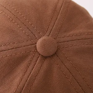 Detalle de la parte superior de gorra marrón con costuras reforzadas y botón forrado
