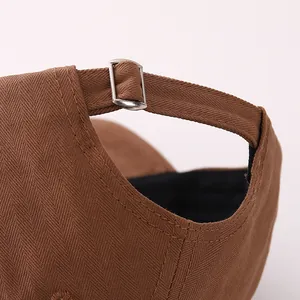 Detalle de la hebilla metálica ajustable y costuras en la gorra de béisbol marrón