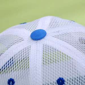 Macro view of breathable white mesh fabric with blue button and embroidered eyelets detail