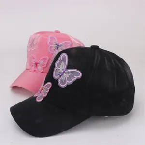 Detail view of pink and black baseball caps with 3D butterfly embroidery for kids