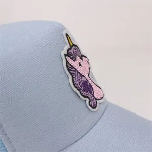 Detailed view of shiny sequin unicorn patch on light blue mesh baseball cap