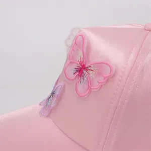 Detail of pink satin kid's hat featuring a delicate 3D butterfly embroidery with gradient wings