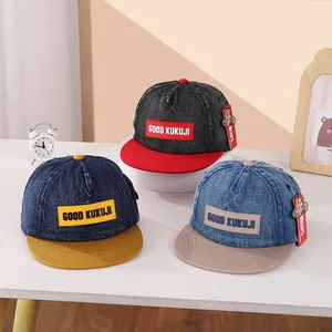 Detailweergave van drie denim kinderhonkbalpetten met platte rand op witte tafel