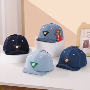 Dettaglio dei berretti da baseball in denim per neonati con patch R in quattro blu