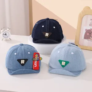 Dettaglio di cappellini da baseball in denim per neonati con logo R e pois blu
