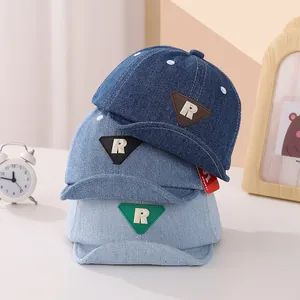 Dettaglio di tre cappellini da baseball in denim per neonati in varie tonalità di blu