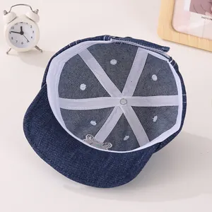 Détail de l'intérieur d'une casquette en denim pour bébé avec broderie et finitions