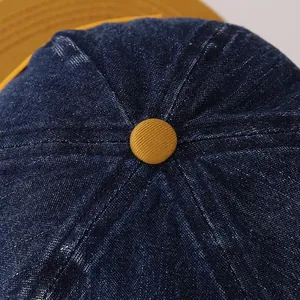 Macro-opname van de blauwe denim honkbalpet met gele knop en stiksels op de kroon van de pet