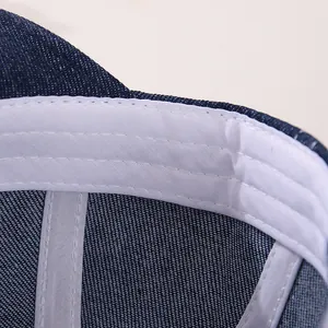 Détail intérieur d'une casquette en denim pour bébé avec bandeau blanc et coutures précises