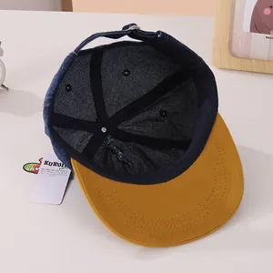 Detail van de binnenkant van de kinderpet met blauwe denim, gele klep en metalen gesp