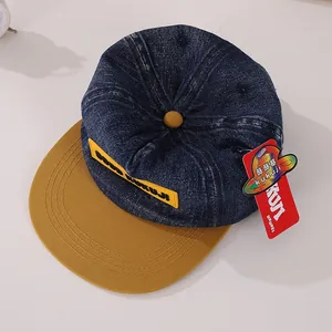 Detailweergave van de denim baseballpet met blauwe body en gele KUKUJI-patch erop