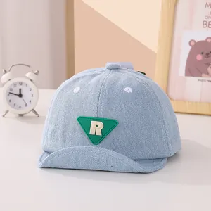 Dettaglio cappellino neonato in denim con patch R verde e visiera morbida