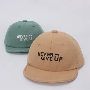 Detalle de gorras de béisbol para bebé en pana verde grisáceo y caqui con bordado