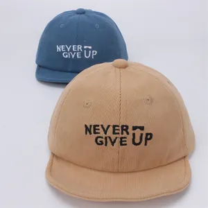 Detalle de gorras de pana para bebé en azul y beige con bordado Never Give Up