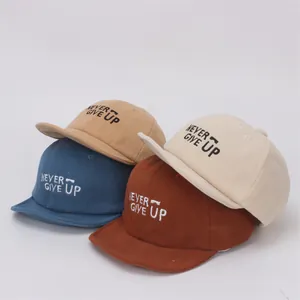 Detalle de cuatro gorras de pana para bebé con bordado Never Give Up en varios colores